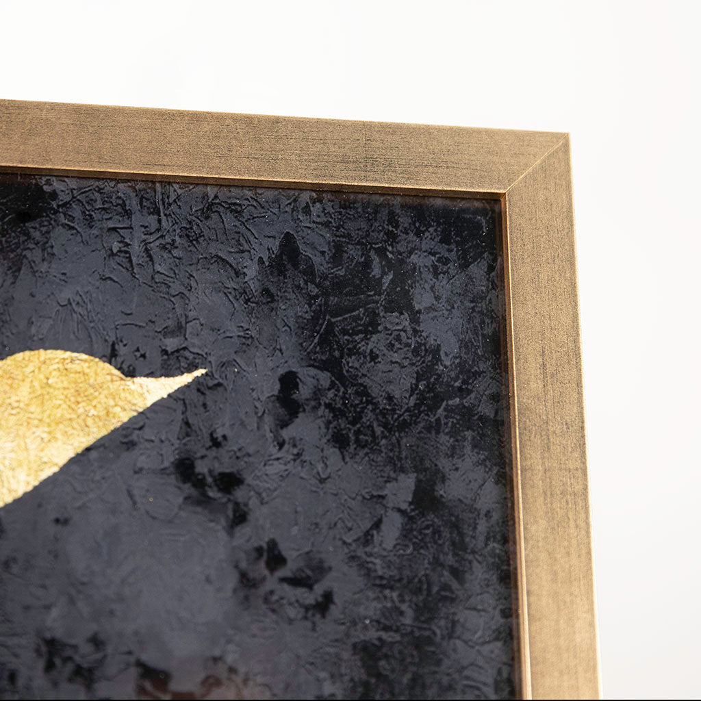 Close-up of a framed abstract artwork with a gold border and black textured background.