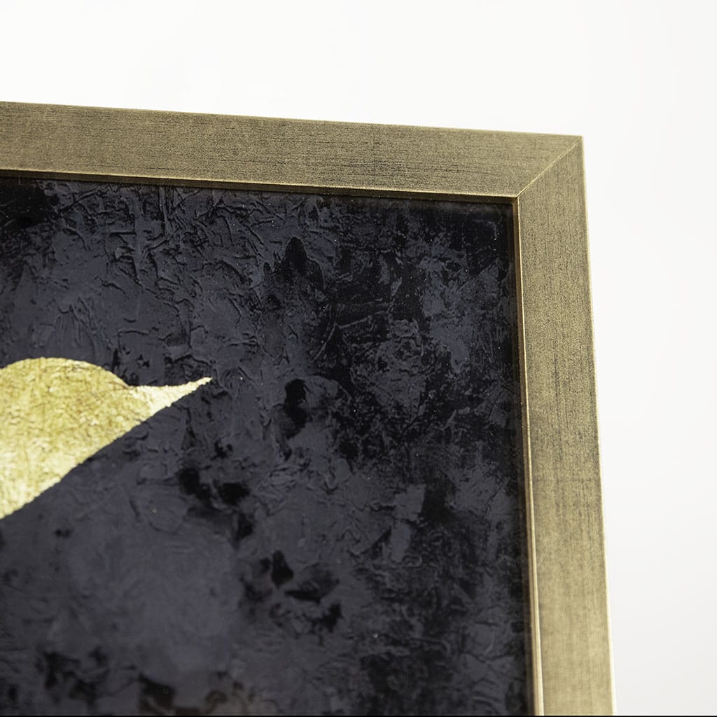 Close-up of a framed abstract artwork with a gold border and black textured background.