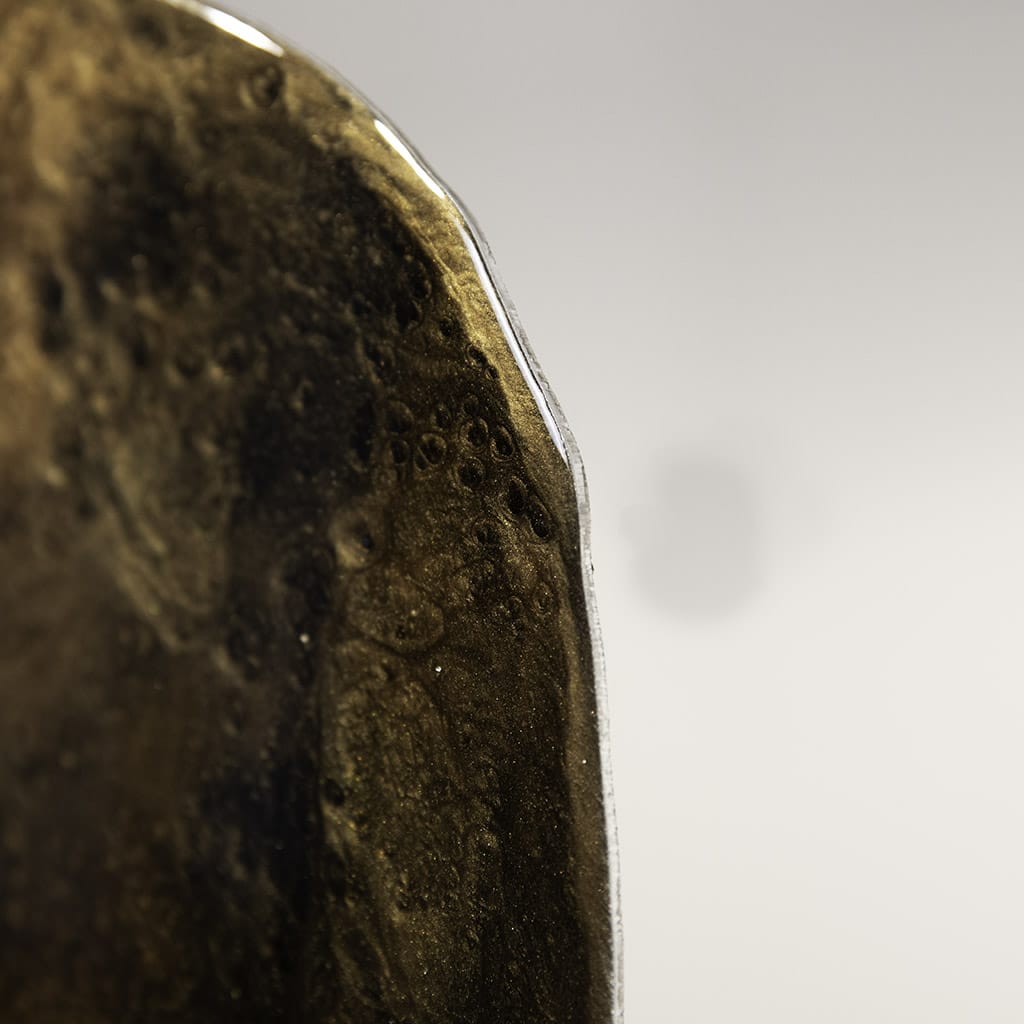 closeup on the rounded glossy edge of Handmade luxury gold resin wall art by Elysian bespoke featuring metallic gold, bronze and black abstract textures on a long rounded panel.Contemporary statement artwork for modern living rooms and luxury interior design.