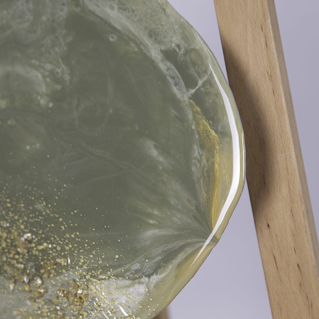 close up of pebble shaped custom resin wall art with a glossy edge. abstract design in greens with an accent of white and gold. gold and white glass crystals detailing. Hand made by paul marshall at elysian bespoke