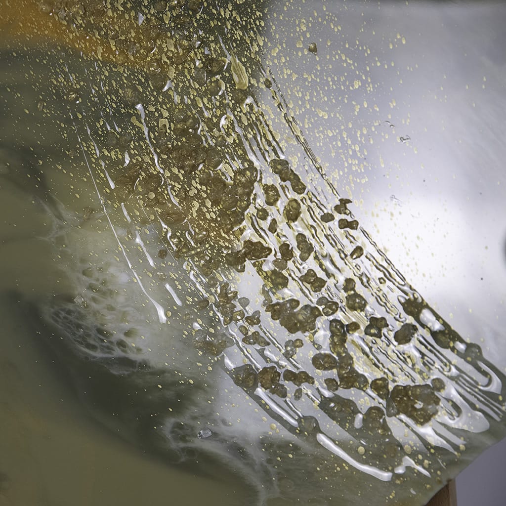 close up detial of glosssy finish on set of 3 pebble shaped custom resin wall art. abstract design in greens with an accent of white and gold. gold and white glass crystals detailing. Hand made by paul marshall at elysian bespoke