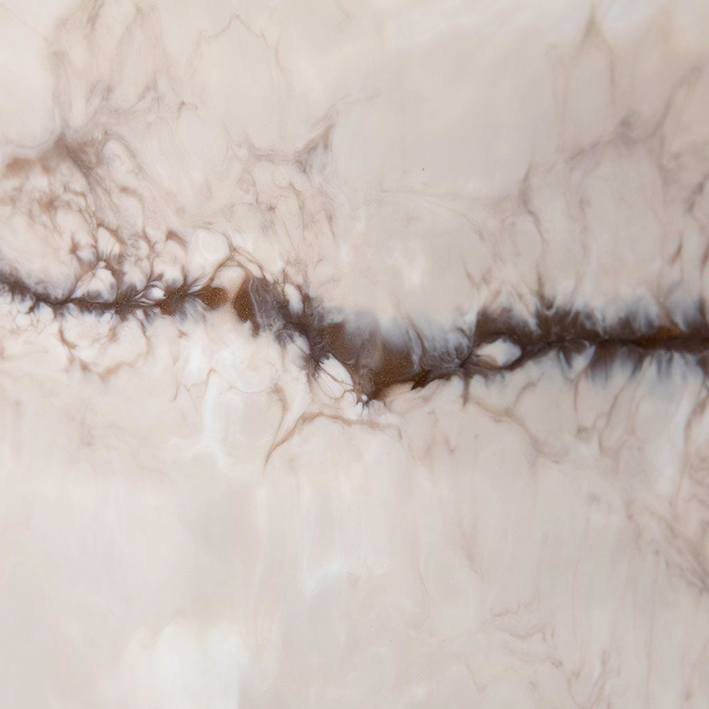 Closeup of resin metal wall art in creams and bronze.