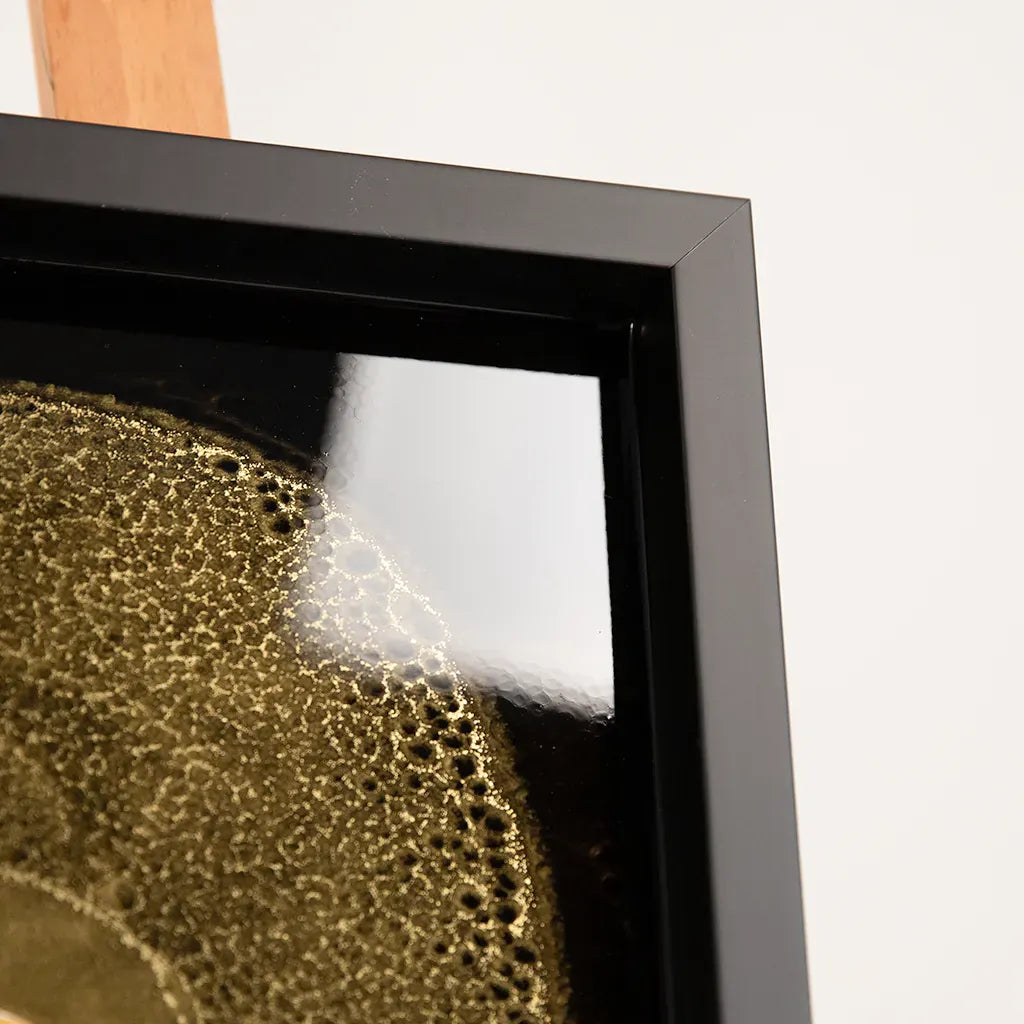 frame closeup of One-of-a-kind Armand de Brignac gold bottle and fragments set in textured metallic resin, handmade and framed by British artist Paul Marshall
